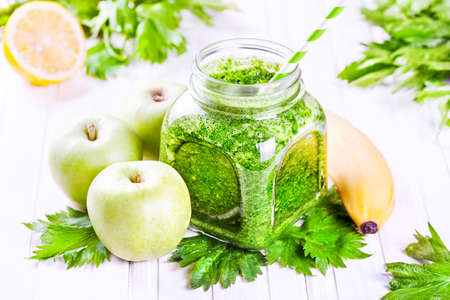 Fresh green smoothie with banana, apples, celery and lemon on white tableの写真素材