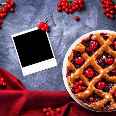 Blank photo frame near homemade cherry pie on grunge backgroundの写真素材