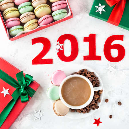 Colorful French macarons and cup of coffee near 2016 year title and present Christmas boxes on white backgroundの写真素材
