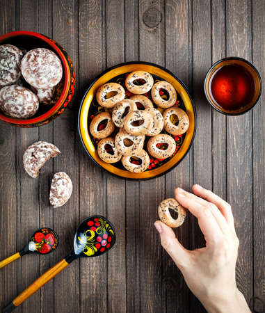 Table with Russian dessert sweet gingerbread and woman hand holding bublik biscuit, wooden spoon...