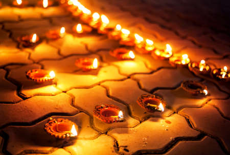 Traditional clay diya lamps lit on the ground during festival diwali celebrationの写真素材