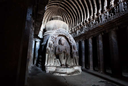 Carved statues of ancient Buddha in big hall with columns in Ellora cave near Aurangabad,...