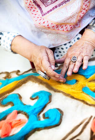Ethnic woman making pattern on the Kazakh blanket in the market at Nauryz celebration in Almaty, Kazakhstanの写真素材