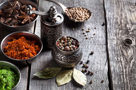 Spices, bronze pepper grinder and spoon with cumin seeds at wooden green backgroundの写真素材