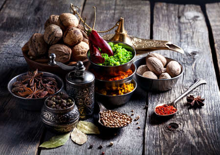 Spices, pepper grinder, spoon with seeds at grey wooden backgroundの写真素材
