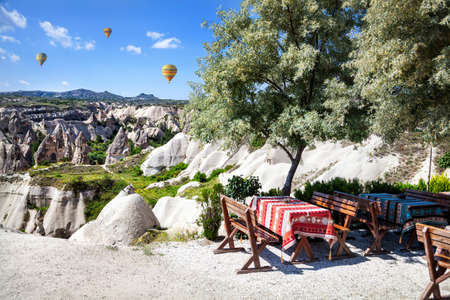 Restaurant in Goreme with view to tufa formations and hot air balloon in Cappadocia, Turkeyの写真素材