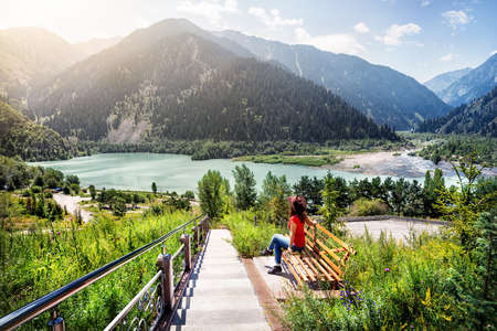 Tourist woman with hat enjoying beautiful view of lake in the mountains in Kazakhstanの写真素材