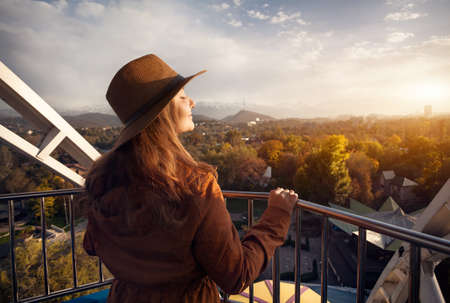 Woman with hat at the cabin of Ferris wheel in the autumn park at sunsetの写真素材