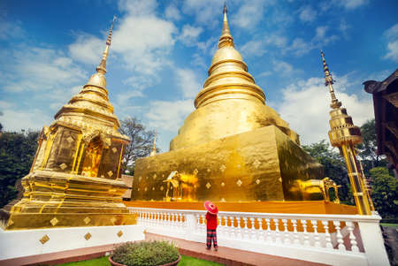 Woman tourist with red traditional Thai umbrella near Golden Stupa at temple Wat Phra Singh in Chiang Mai, Thailandの写真素材