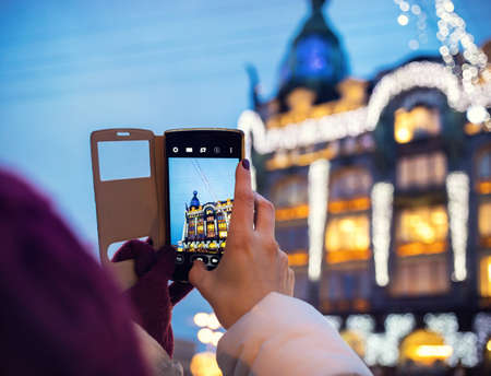 Woman taking pictures of Book Home Zinger Building by her Smartphone in Saint Petersburg