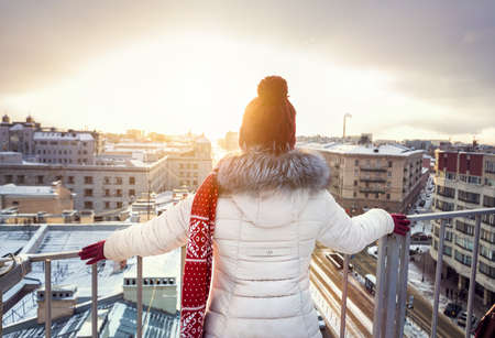 Woman in Christmas Hat and red scarf on the roof at snow fall in Saint Petersburg, Russiaの写真素材