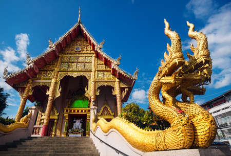 Statue of golden dragons near stairs in Buddhist temple of Chiang Rai, Thailand