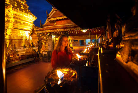 Woman tourist looking at prayer candle lights at Buddhist Temple Doi Suthep at night in Chiang Mai, Thailandの写真素材