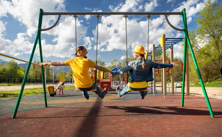 Happy couple in blue and yellow clothes rides at swing in children park in Almaty, Kazakhstanの写真素材