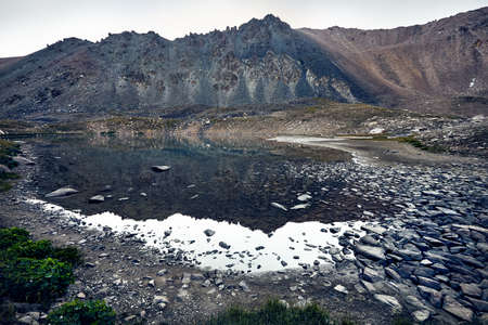 Landscape of Rocky Mountains and lake at grey overcast sky backgroundの写真素材