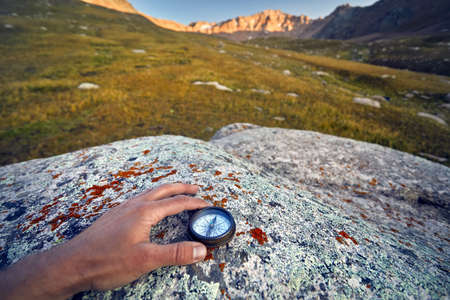 Tourist hand with vintage compass on the mountains background. Travel and adventure concept.の写真素材