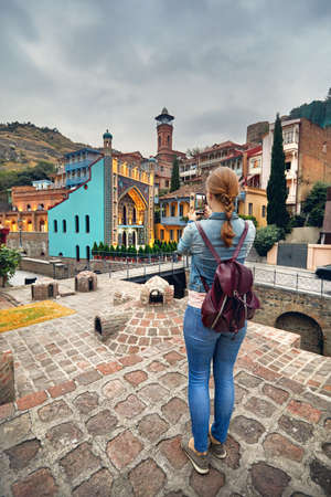 Tourist woman in brown jacket Taking picture of Public Sulfuric bath by her smartphone in Tbilisi,...