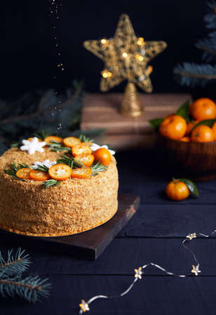 Christmas Honey cake with rosemary and oranges on black background.