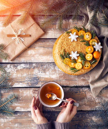 Christmas Honey cake on the table. Woman holding tea with berry near decorated present at breakfast.の写真素材