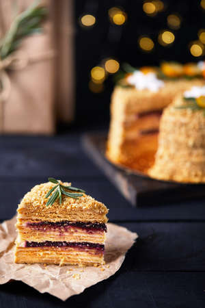 Piece of Christmas Honey cake with rosemary and oranges on black background.