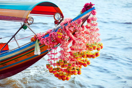 Traditional Thai longtail boat with flower garland close up in Chao Phraya river in Bangkokの写真素材