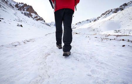 Hikers legs walking around snowy mountain. Freedom of trekking concept.
