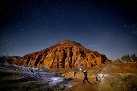 Man with head light in the desert at night sky background. Travel, adventure and expedition concept.の写真素材
