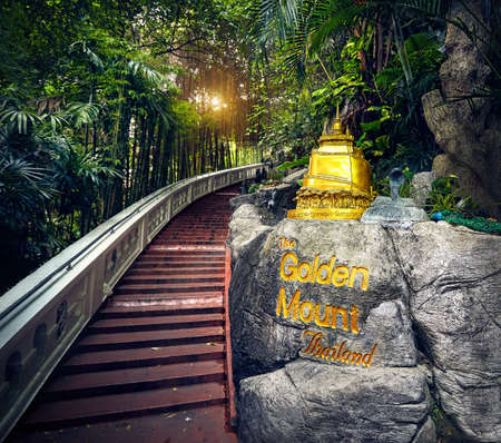 Golden Stupa statue in the tropical jungle near the stairs in Wat Saket Golden Mountain Temple famous Landmark in Bangkok, Thailandの写真素材