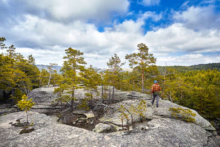 Man in brown jacket walking to the beautiful forest in Karkaraly national park in Karkaralinsk,...