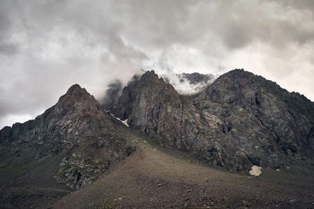 Beautiful Landscape of foggy rocky mountains at overcast dark sky background in Kazakhstanの写真素材