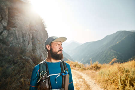 Portrait of bearded runner athlete with backpack in the mountains at sunriseの写真素材