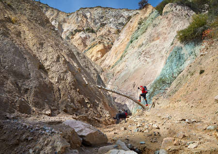 Old man in red shirt and black dog hiking in the mountains. Outdoor travel concept