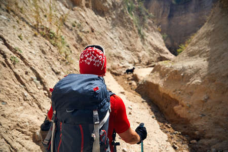 Tourist in red hat with backpack in the canyons, back view