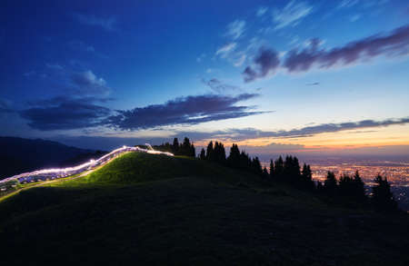 Light trace of runners led on the race in the mountains at night city lights of Almaty in Kazakhstan, Central Asiaの写真素材