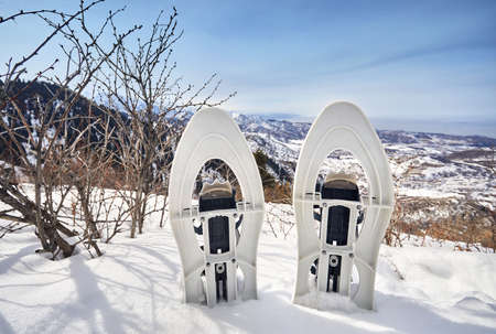 Snowshoes in the snow on the mountain peak against blue skyの写真素材