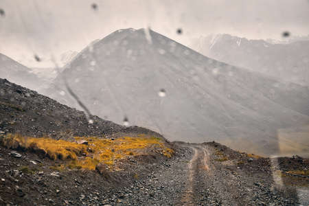 Road in beautiful mountain valley viewed from the car window with raindrops. Travel and adventure concept.の写真素材