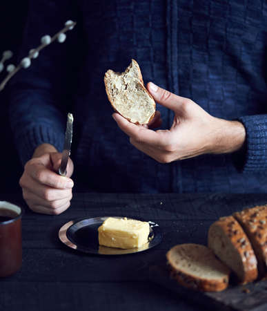 Man eating bread with butter on dark backgroundの写真素材