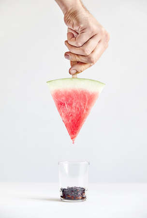Man holding water melon clean slice by the stick on white background. All seeds in the glass.の写真素材