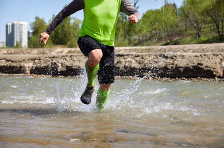 Legs of runner close up the river with splashesの写真素材