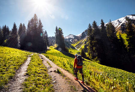 Tourist in orange shirt with backpack walking in the mountains. Outdoor travel conceptの写真素材