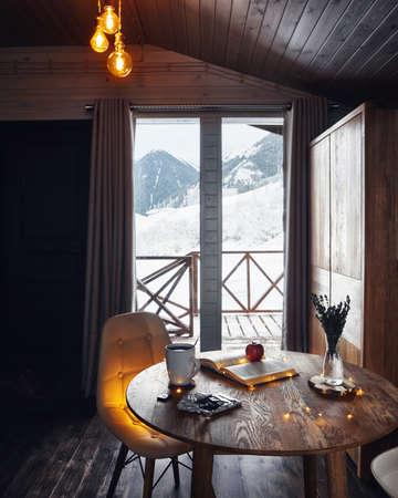 Loft interior with warm lights in wooden winter cottage with beautiful Mountain Viewの写真素材