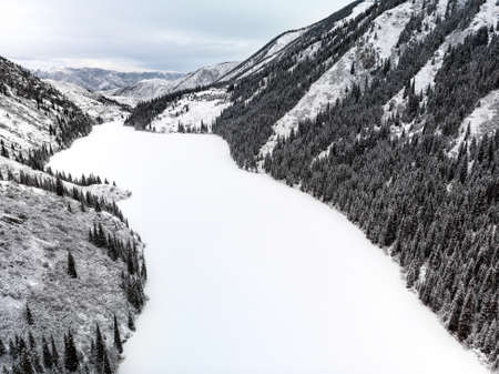 Aerial view of Kolsay mountain lake and forest at winter time in the mountains of Kazakhstan. Drone shot, top view.の写真素材