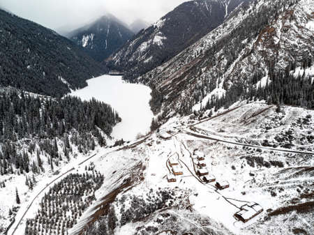 Aerial view of Kolsay mountain lake and village houses at winter time in the mountains of Kazakhstan. Drone shot, top view.の写真素材