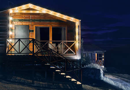 Modern wooden house decorated with yellow glowing bulbs at the mountain resortのeditorial素材