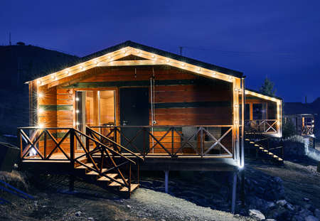 Modern wooden house decorated with yellow glowing bulbs at the mountain resortのeditorial素材