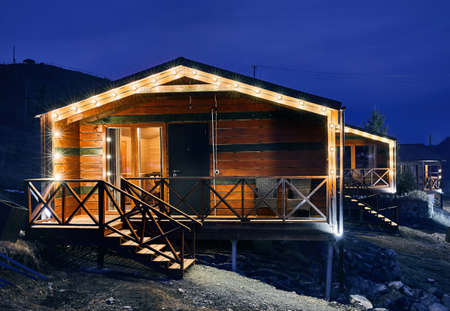 Modern wooden house decorated with yellow glowing bulbs at the mountain resortのeditorial素材