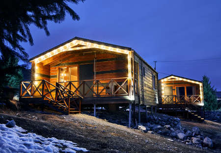 Modern wooden houses decorated with yellow glowing bulbs at the mountain resortのeditorial素材