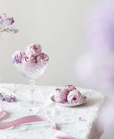 Violet sweet homemade Zephyr or Marshmallow from black currant around lilac flowers on white table cloth and light backgroundの写真素材
