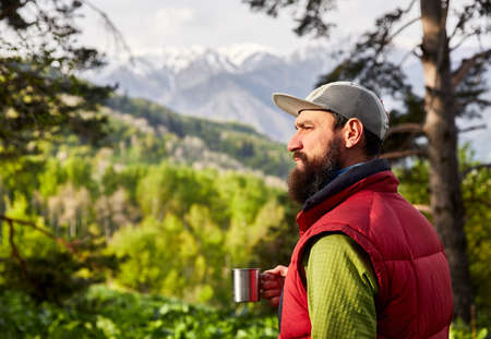 Portrait of bearded tourist is cup of coffee in the lush forest at mountains の写真素材