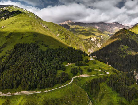 Aerial view of the road in the mountain valley with lush forest in Kazakhstanの写真素材